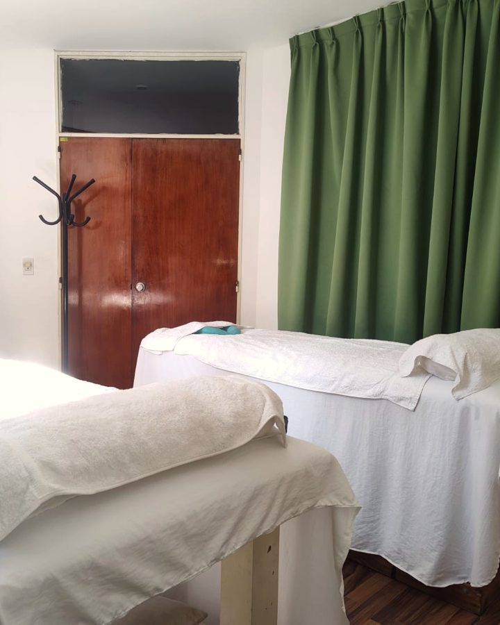 Sala con cortina verde y camillas preparadas con toallas blancas